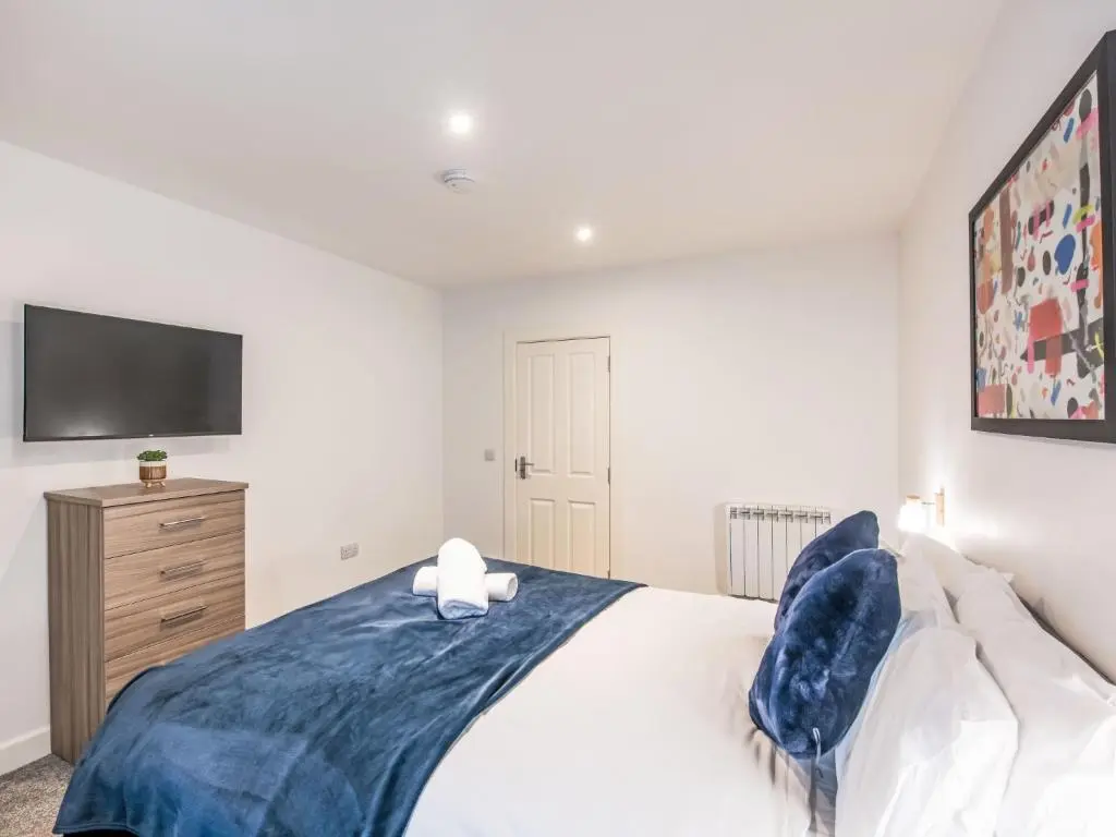 a bedroom with a bed with a tv on the wall at Apartment Fishertown Apartment by Interhome in Nairn