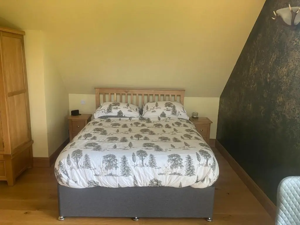 a bedroom with a bed with a comforter and pillows at Dalvourn West Wing , Farr by Inverness in Tordarroch