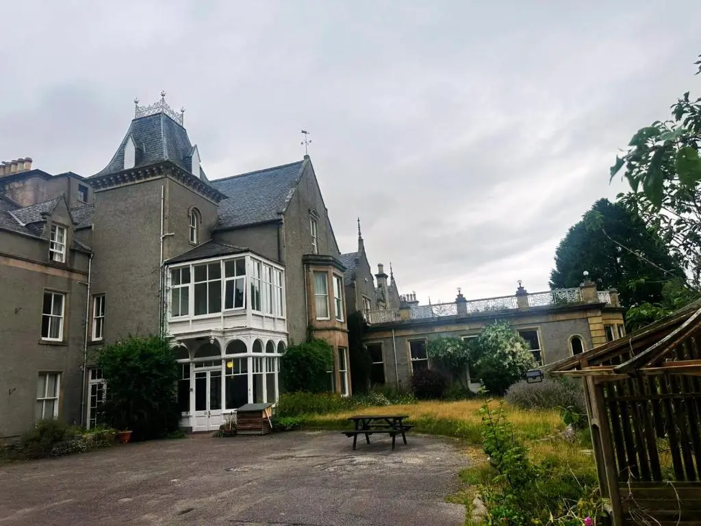 a large house with a picnic table in front of it at Cluny Hill Hotel in Forres
