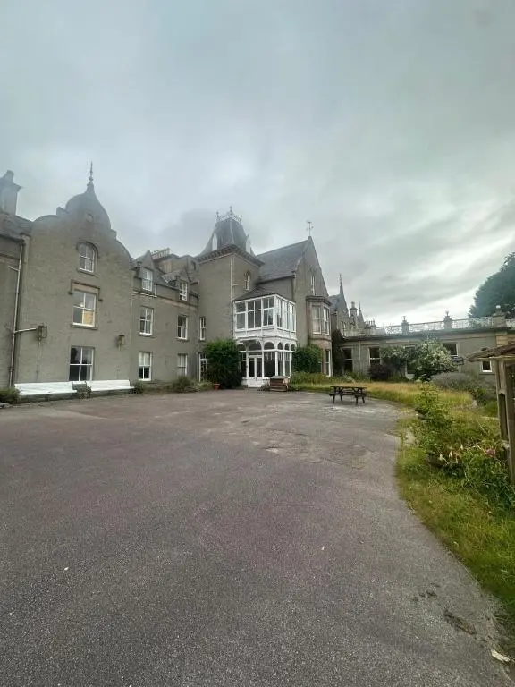 a large building with a parking lot in front of it at Cluny Hill Hotel in Forres