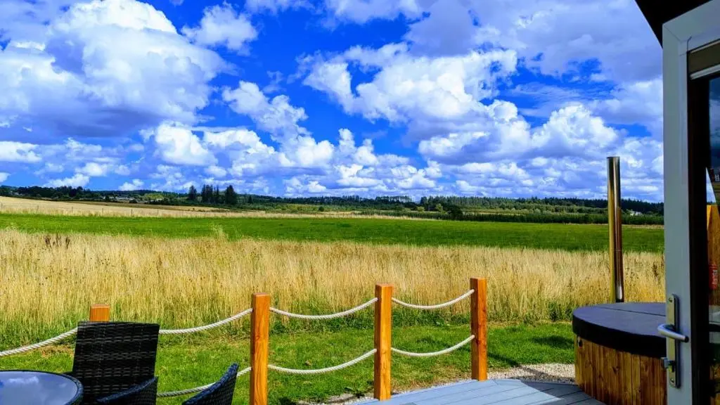 a porch with chairs and a fence and a field at Barn Owl Pod - Speyside in Carron
