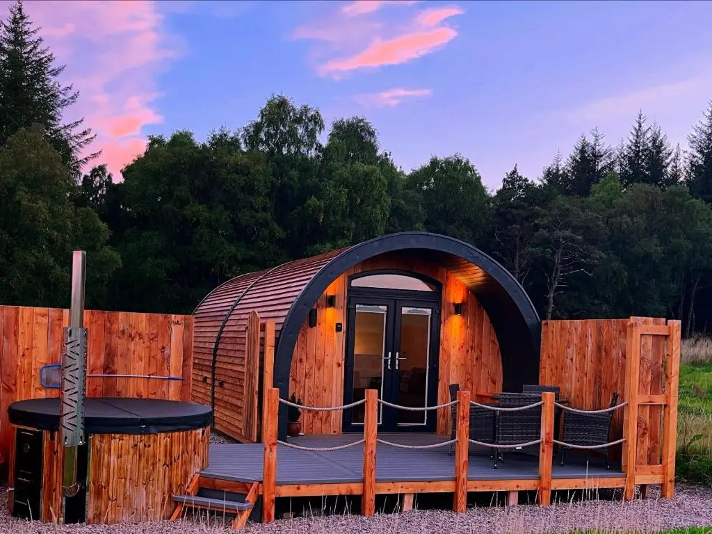 a circular house with a deck and a table and chairs at Barn Owl Pod - Speyside in Carron