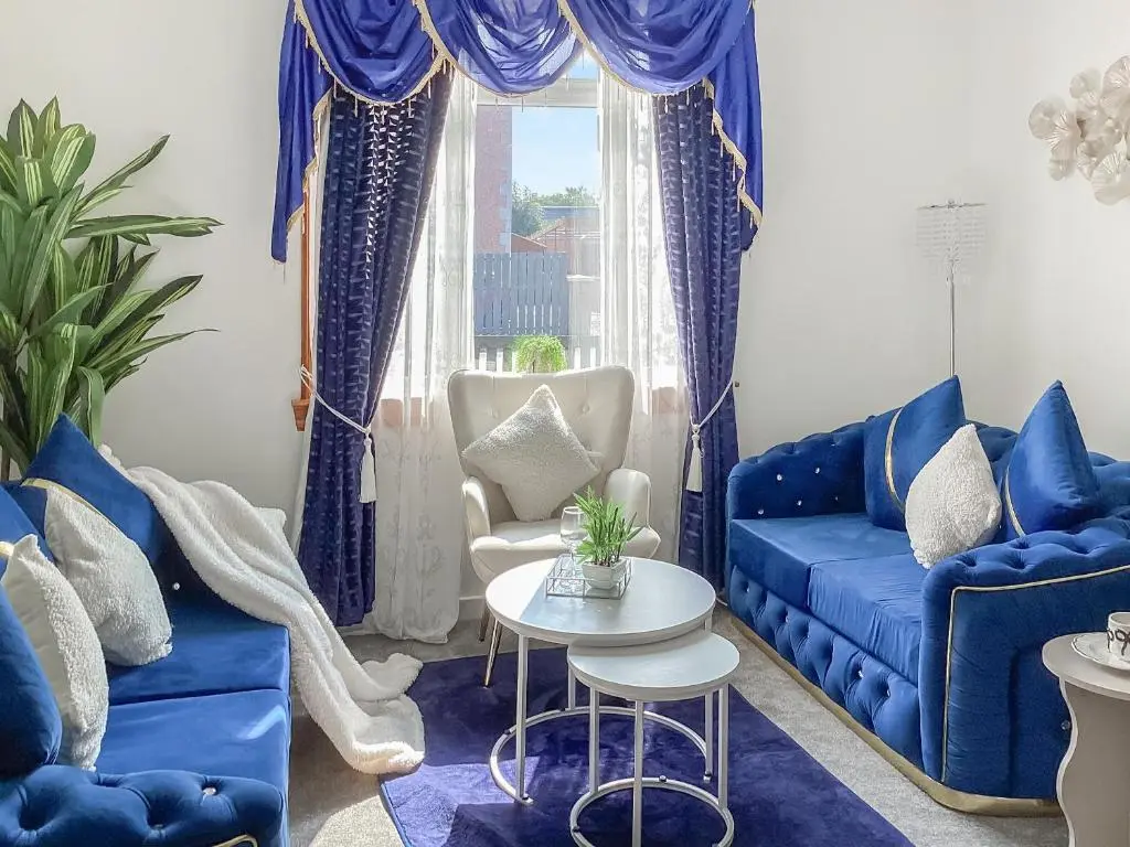 a living room with blue couches and a table at Amayrah Cottage in Inverness