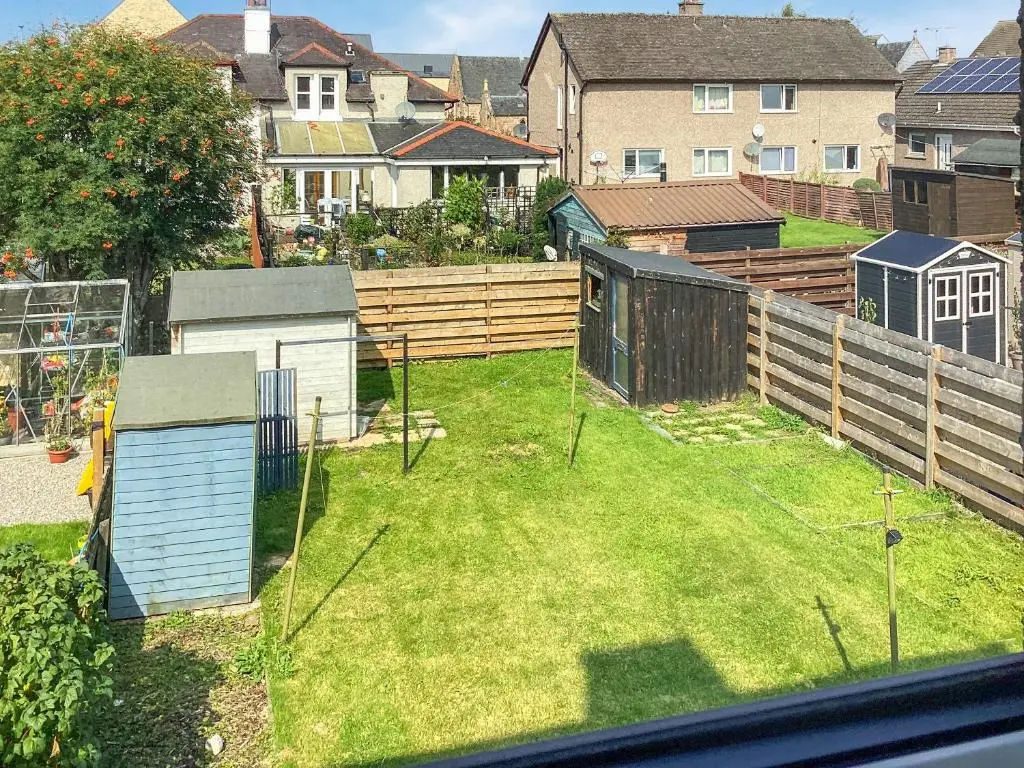 a backyard with a fence and a yard with grass at Amayrah Cottage in Inverness
