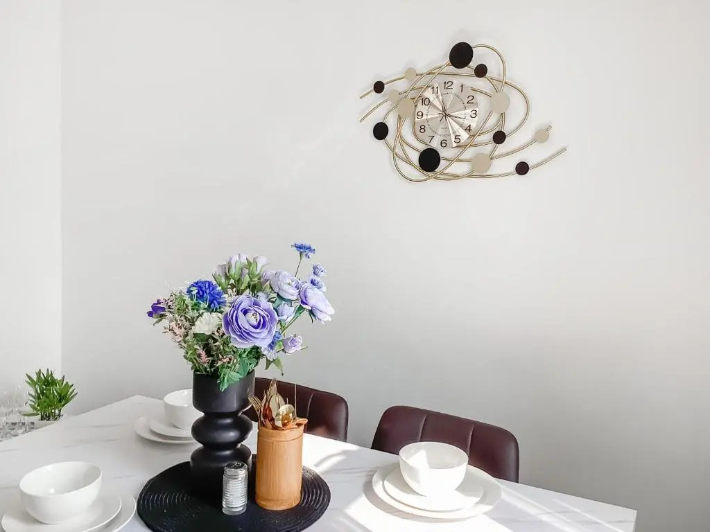 a table with a vase of flowers and a clock at Amayrah Cottage in Inverness