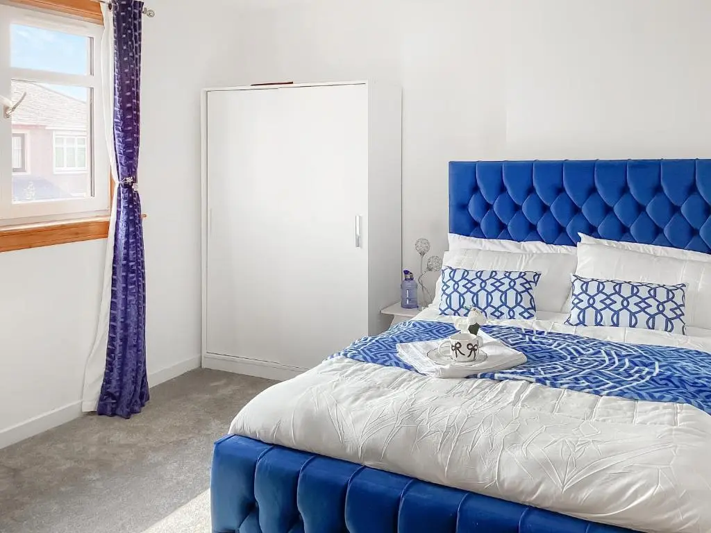 a blue bed with a blue headboard in a bedroom at Amayrah Cottage in Inverness