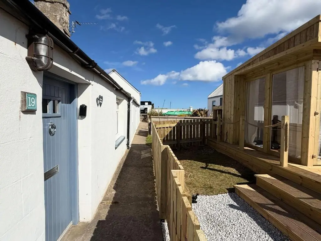 a walkway between two buildings with a fence at Seatown Cottage - Stone's throw from beach in Lossiemouth