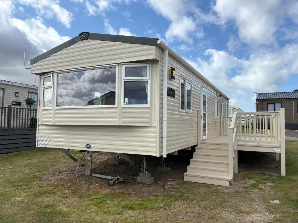 a white tiny house with a staircase in a yard at Summer breeze in Lossiemouth