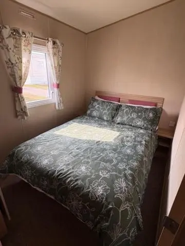 a bedroom with a bed with a comforter and a window at Summer breeze in Lossiemouth
