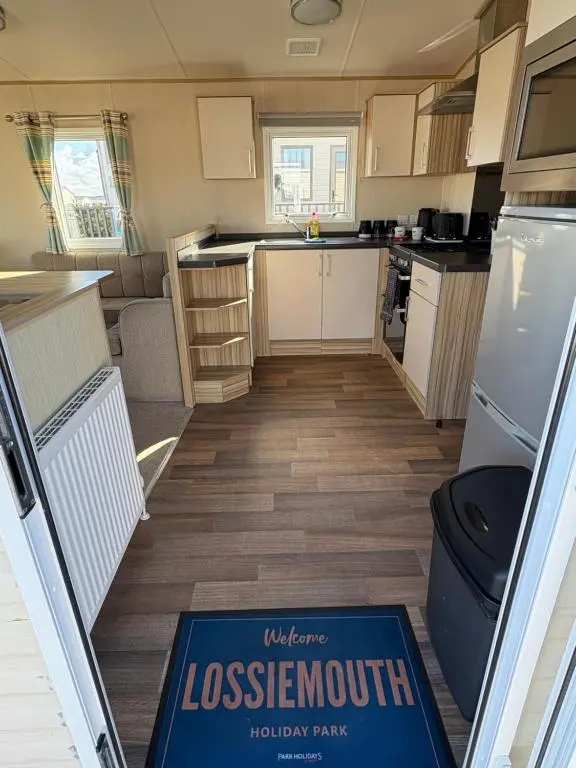 a kitchen with a lassenout sign on the floor of a caravan at Summer breeze in Lossiemouth