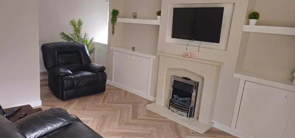 a living room with a fireplace and a chair and a television at Coastal Bliss, Rosehearty, Fraserburgh in Rosehearty