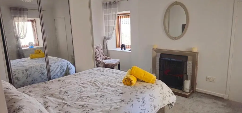 a bedroom with a bed and a mirror and a fireplace at Coastal Bliss, Rosehearty, Fraserburgh in Rosehearty