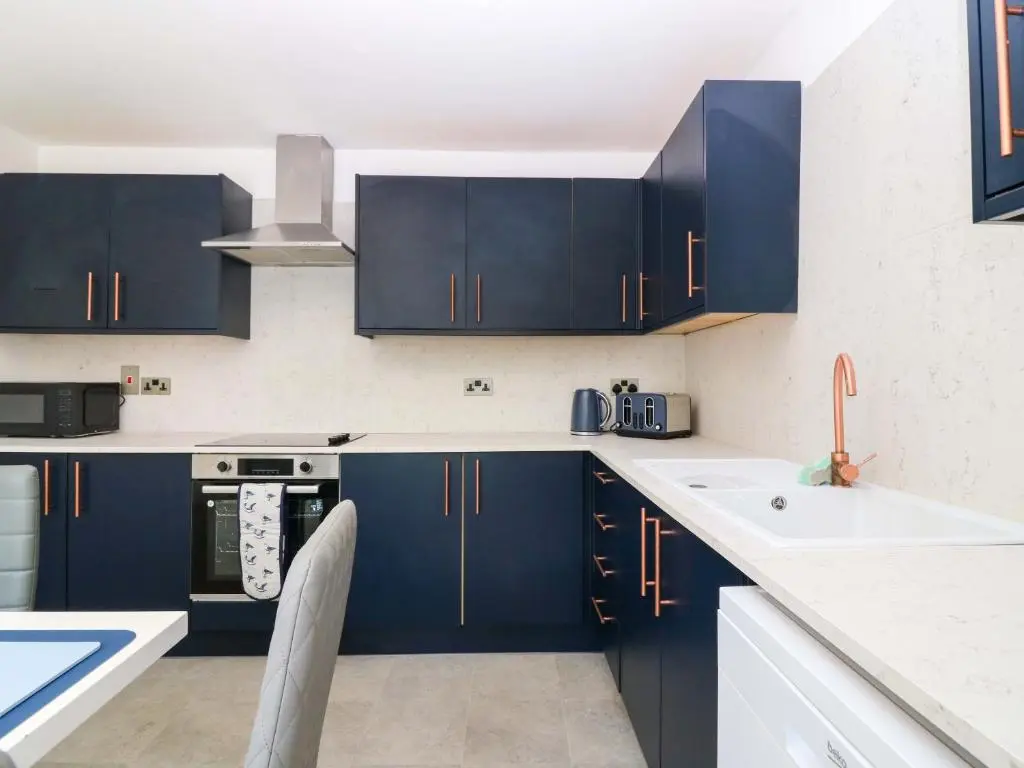a kitchen with navy blue cabinets and a sink at No 9 North St in Fraserburgh