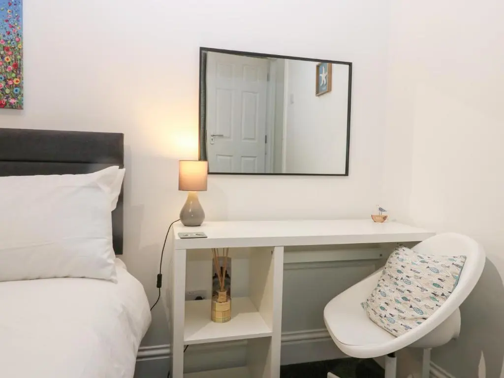 a bedroom with a bed and a mirror and a chair at No 9 North St in Fraserburgh