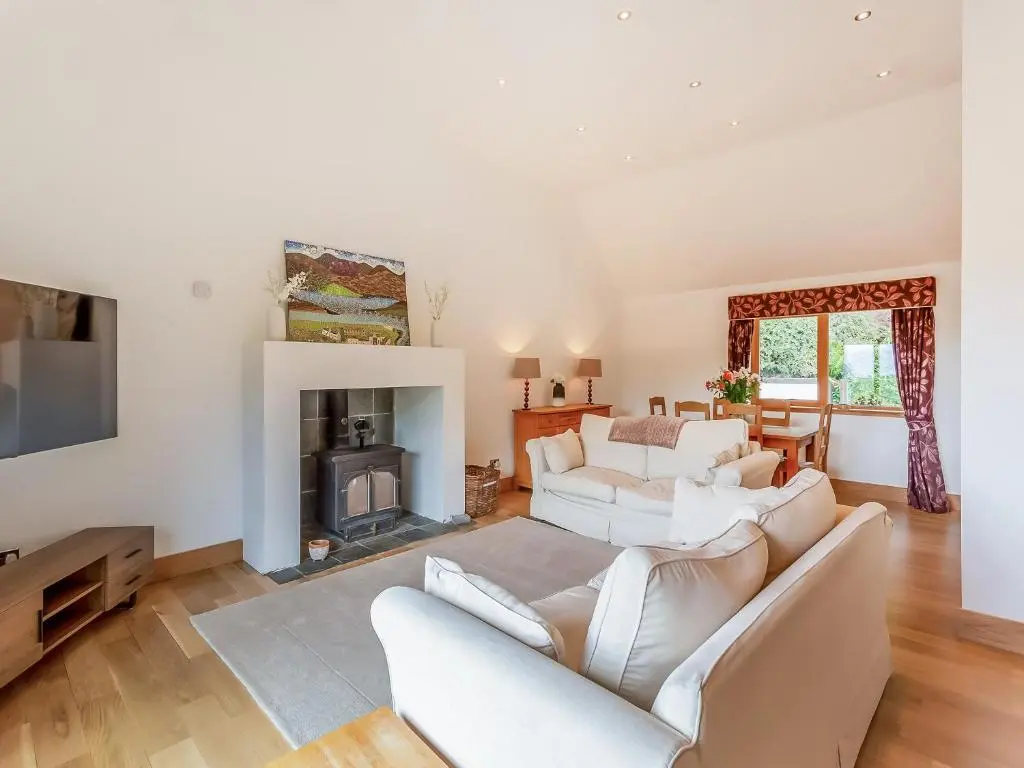 a living room with white furniture and a fireplace at Corrie Burn Villa in Ullapool