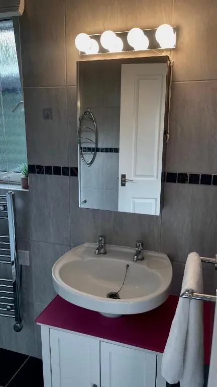 a bathroom with a white sink and a mirror at Birch Cottage in Aviemore