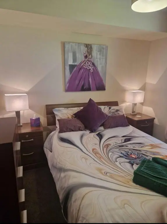 a bed in a room with two lamps and a painting at Bright 2 Bed Corner Flat - Great Location in South Kessock