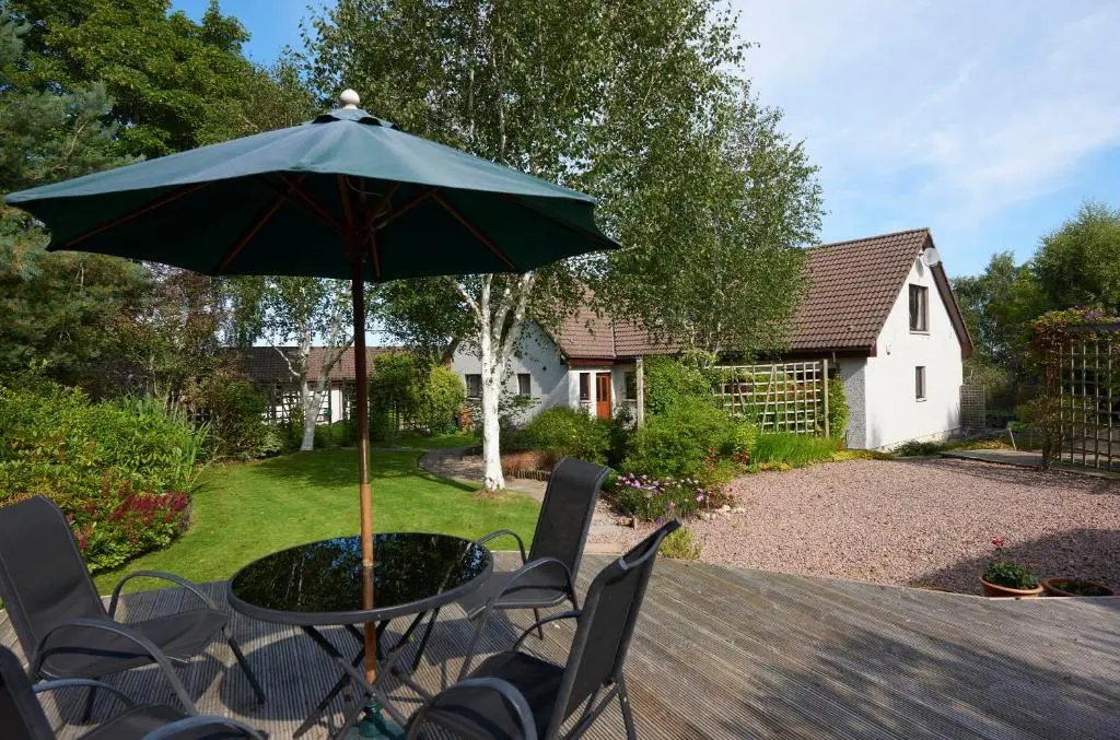a table and chairs with an umbrella on a patio at By the Brae in Inverness