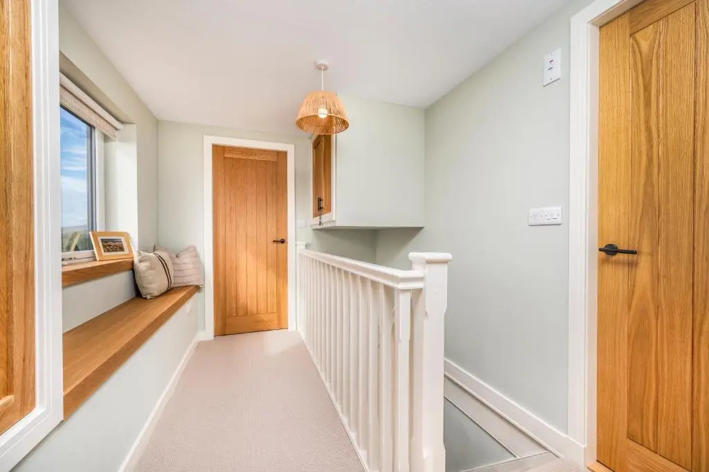 a hallway with white walls and a wooden door at The Top House, Lothmore in Helmsdale