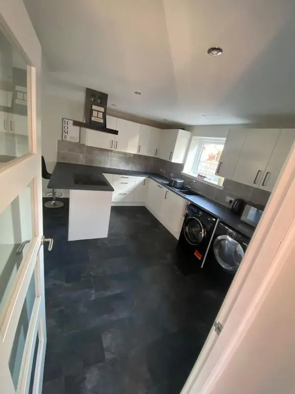 a kitchen with white cabinets and a black floor at Inward Oasis Relax and unwind in Buckie
