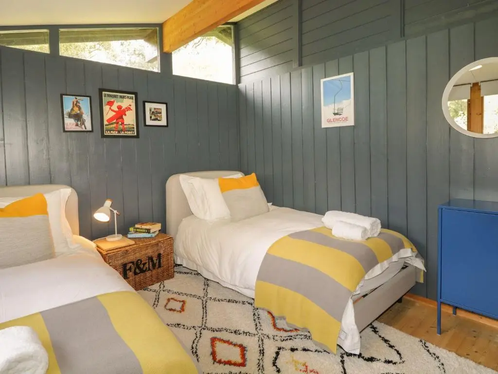 a bedroom with two beds in a room with blue walls at Blue Pine Lodge in Dornoch