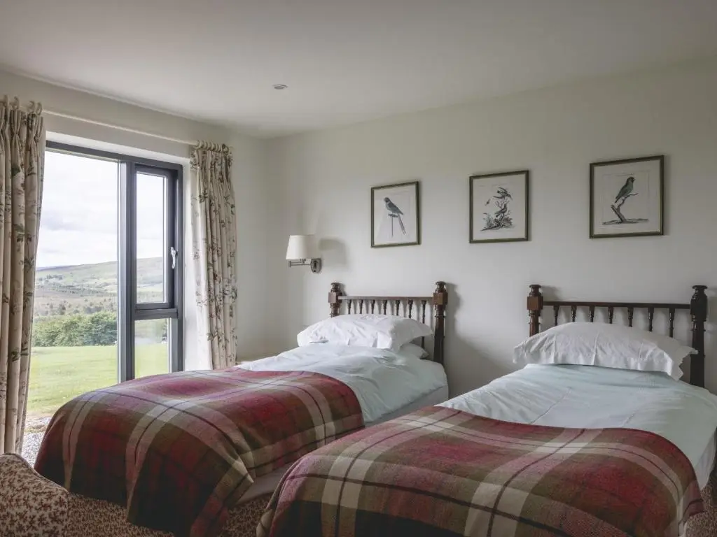 two beds in a room with a window at Phils House in Lairg