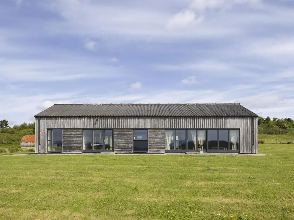 a modern house with a large grass field at Phils House in Lairg