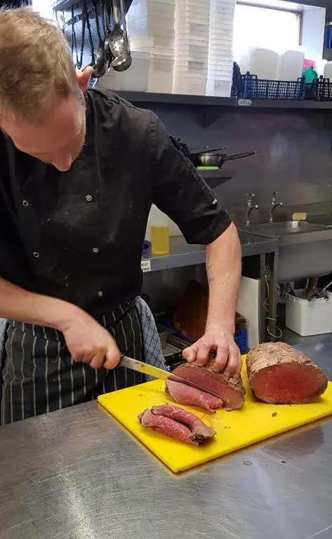 a man preparing meat on a yellow cutting board at The Havelock in Nairn
