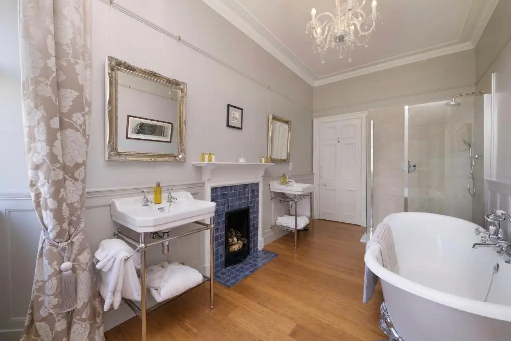 a bathroom with a tub and a sink and a fireplace at Lys-Na-Greyne Country House in Aboyne