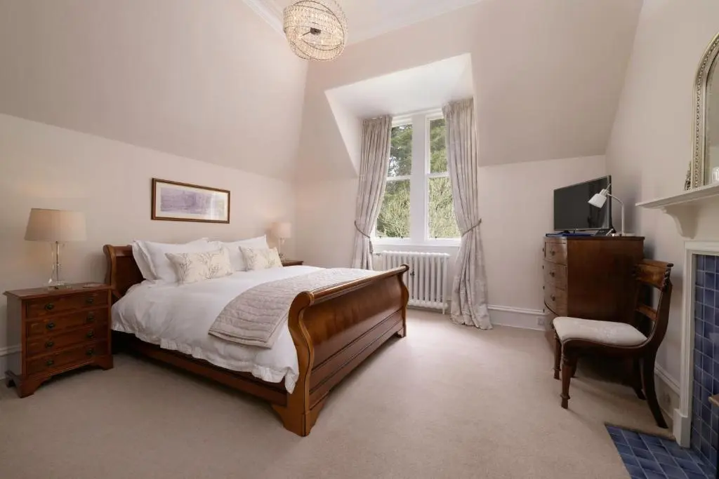 a bedroom with a bed and a chair and a window at Lys-Na-Greyne Country House in Aboyne