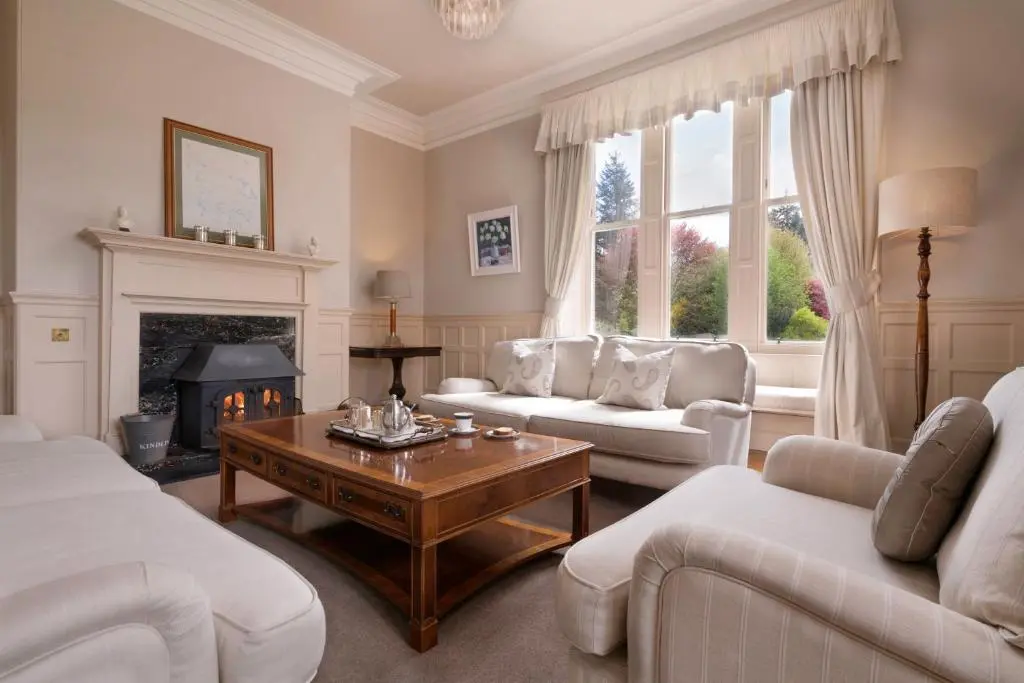 a living room with white furniture and a fireplace at Lys-Na-Greyne Country House in Aboyne