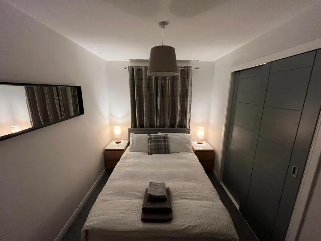a small bedroom with a bed with two lamps at 24 Two bedroom apartment Culloden Inverness Highlands in Culloden