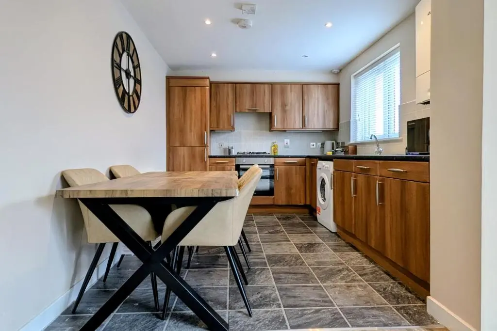a kitchen with wooden cabinets and a table and chairs at The Wee Heilan' Drochaid in Inverness
