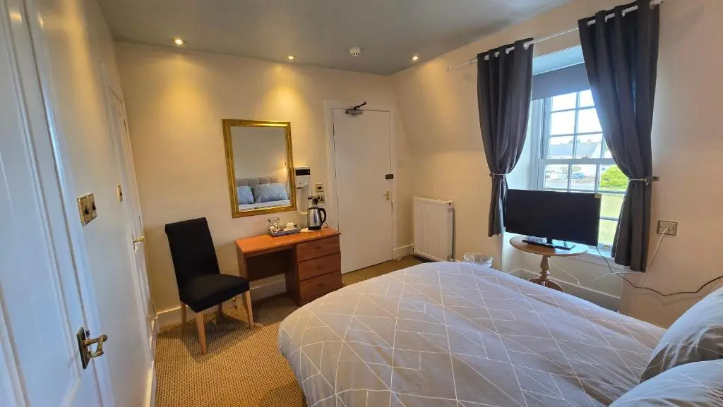 a bedroom with a bed and a desk and a television at The Pitfour Arms Hotel in Mintlaw