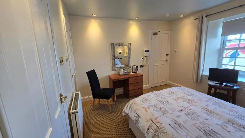 a bedroom with a bed and a desk and a mirror at The Pitfour Arms Hotel in Mintlaw