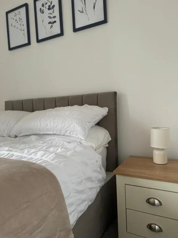 a bed with white sheets and pillows next to a table at Stephen's Brae Apartment, Inverness City Centre in Inverness