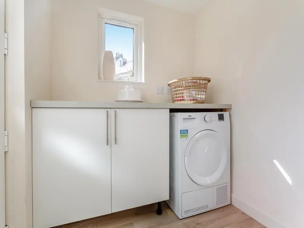 a white bathroom with a washing machine under a counter at Tanera in Wick