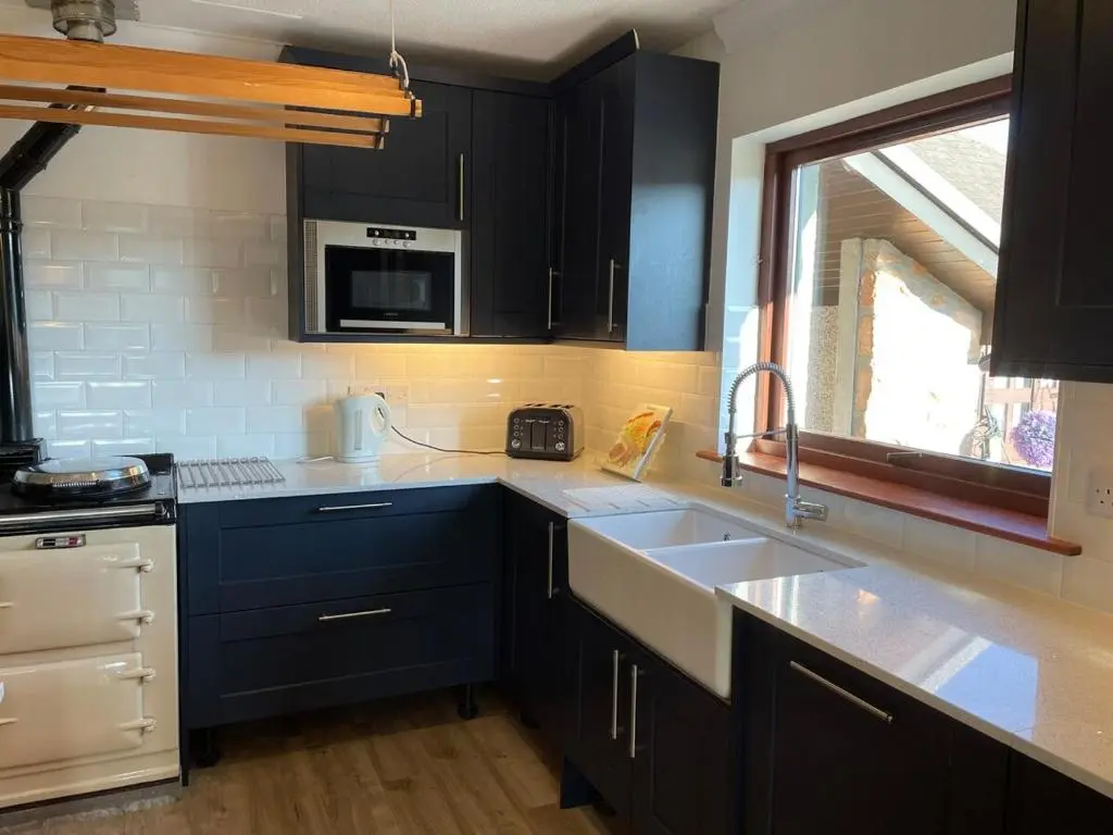 a kitchen with dark blue cabinets and a sink at Abalone Accommodation in Culbokie