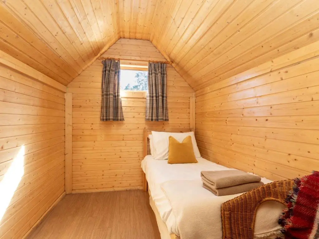 a small room with a bed in a wooden cabin at Apartment Ghillie's Bothy by Interhome in Coldstone