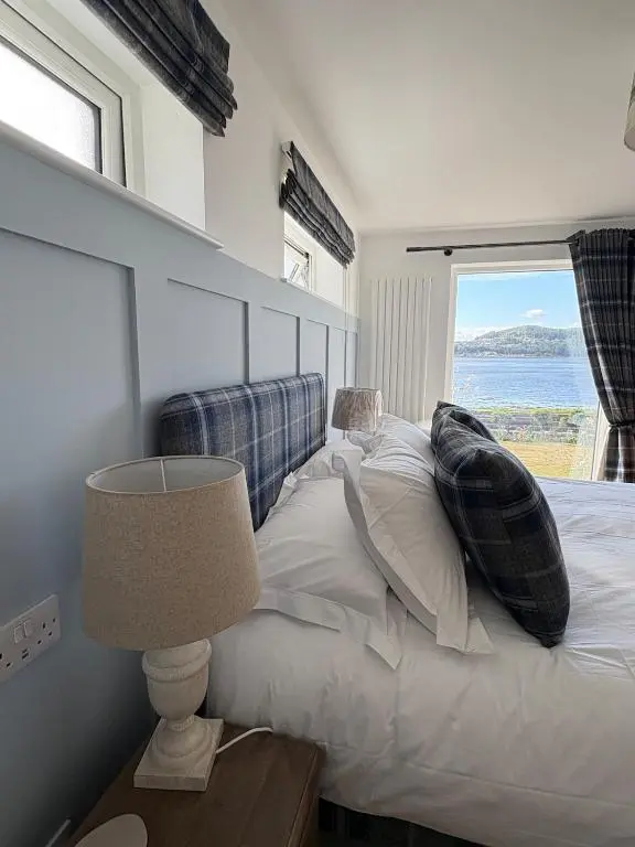 a bedroom with a large bed with a window at Seaside Retreat - Quiet Seafront Spot with Free Parking in North Kessock