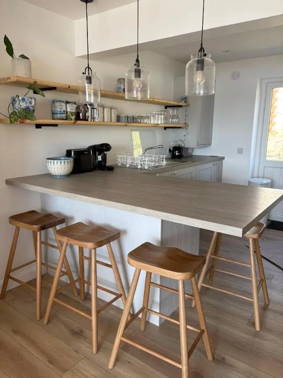 a kitchen with a large counter with three stools at Seaside Retreat - Quiet Seafront Spot with Free Parking in North Kessock