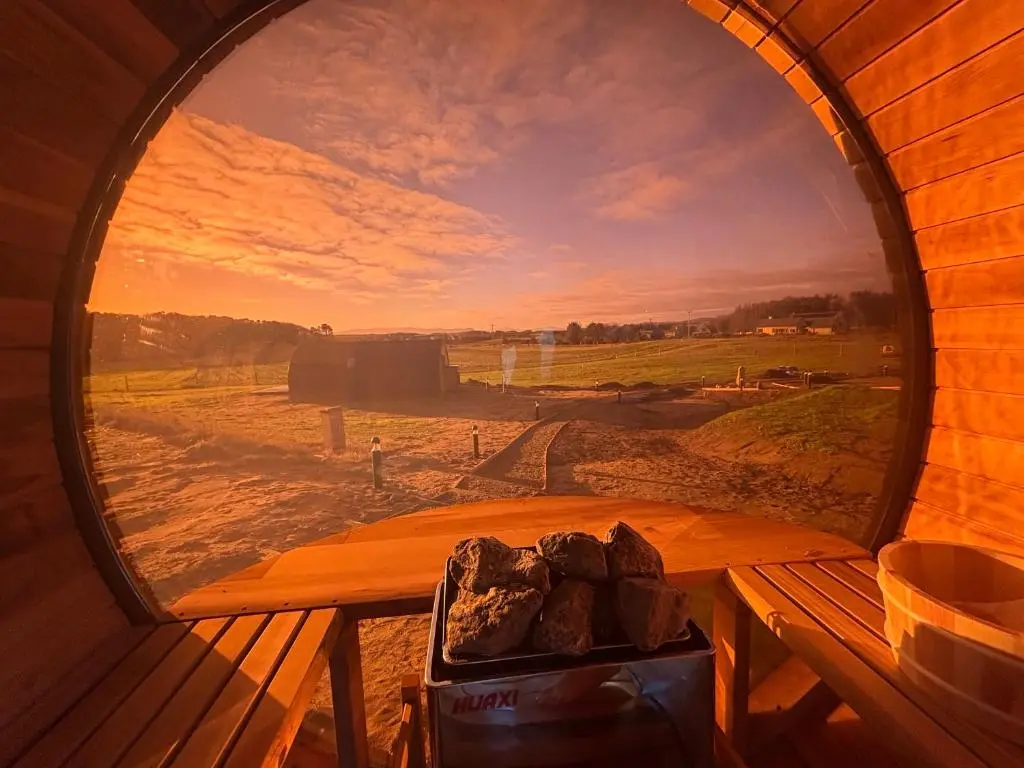 a round window in a cabin with a view of a field at Dornoch Pods in Dornoch