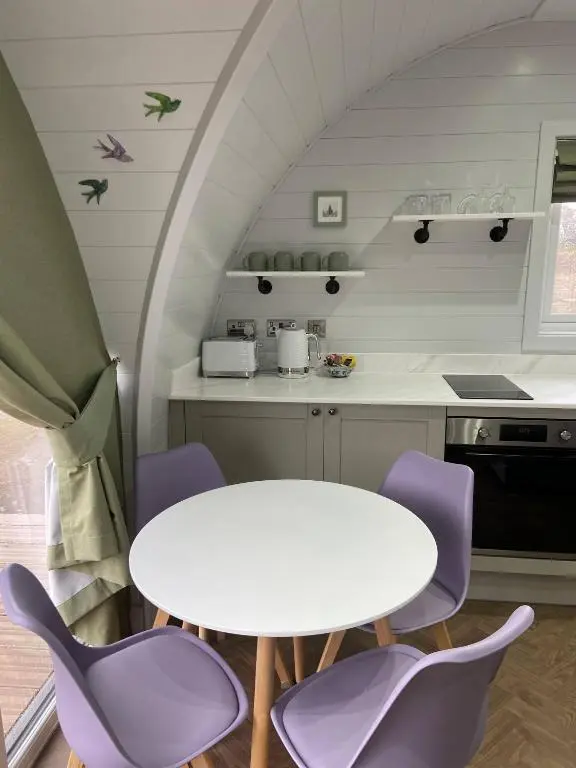 a kitchen with a white table and purple chairs at Dornoch Pods in Dornoch