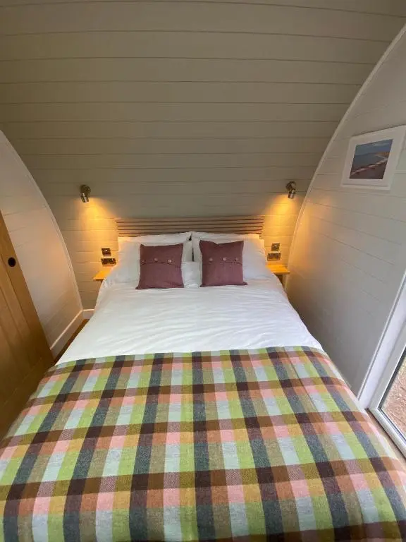 a bed with two pillows in a small room at Dornoch Pods in Dornoch