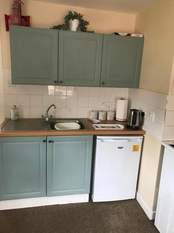 a small kitchen with green cabinets and a sink at Struan Cottage in Ballater