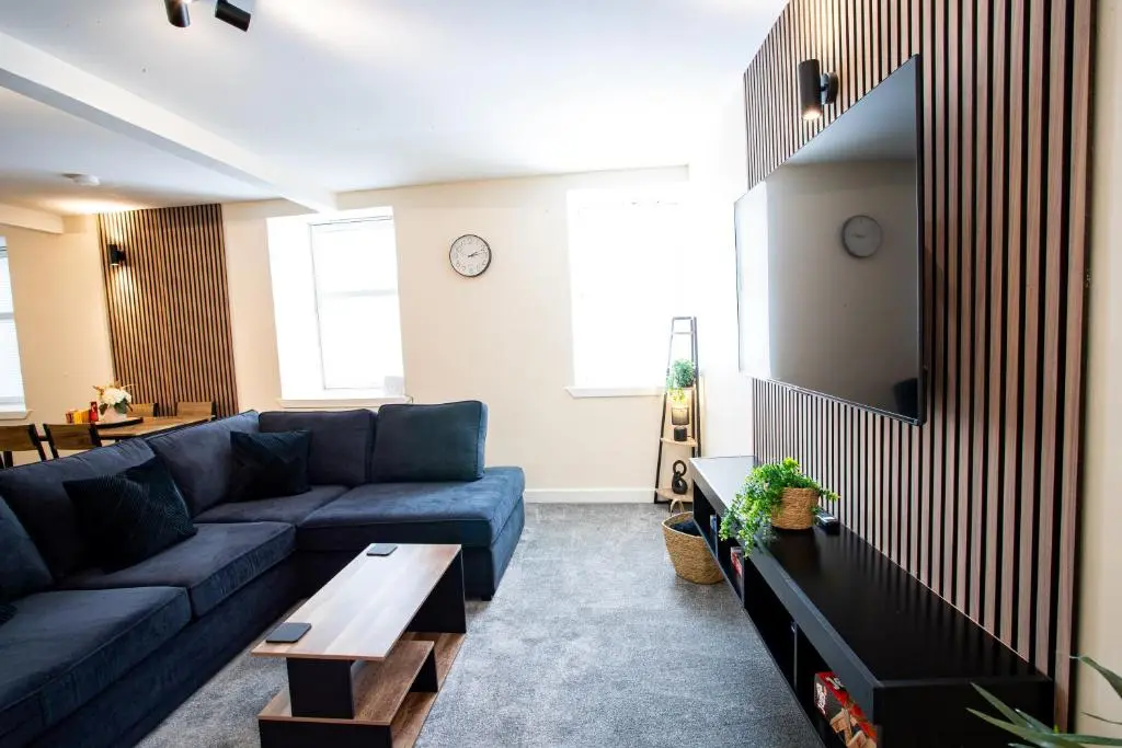 a living room with a blue couch and a table at Baron Taylor Stays in Inverness