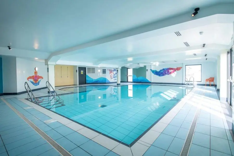 a large swimming pool with two chairs in a building at Whispering Dunes - Silver Sands Holiday Park in Lossiemouth