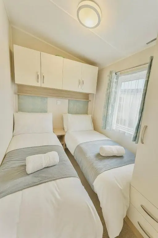 two beds in a small room with a window at Whispering Dunes - Silver Sands Holiday Park in Lossiemouth