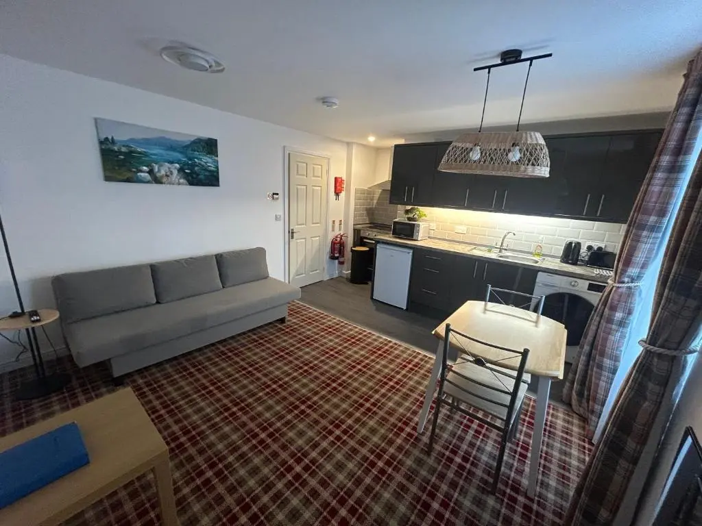 a living room with a couch and a kitchen at Chloes Holiday Apartments in Inverness