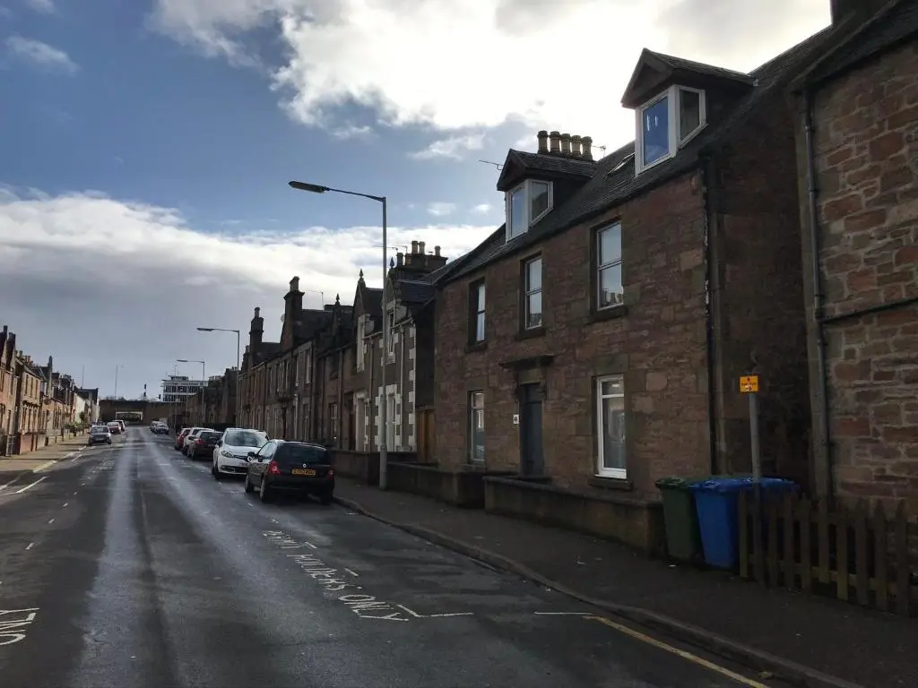 an empty street with cars parked on the side of buildings at Chloes Holiday Apartments in Inverness